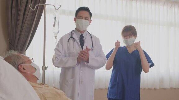 亚洲医生和护士用微笑鼓掌的方式鼓励躺在床上的病人疫情大流行期间患者和医护人员佩戴口罩预防感染