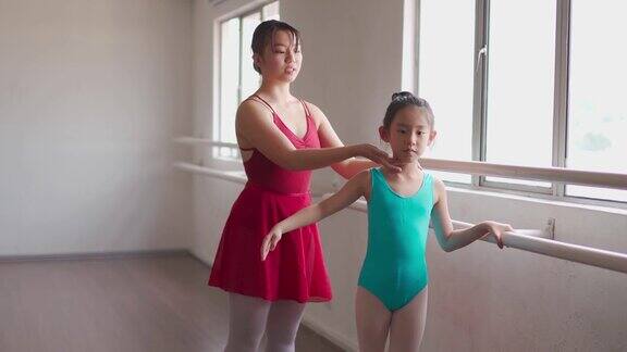 亚洲中国少女芭蕾舞演员训练她的年轻女学生在工作室