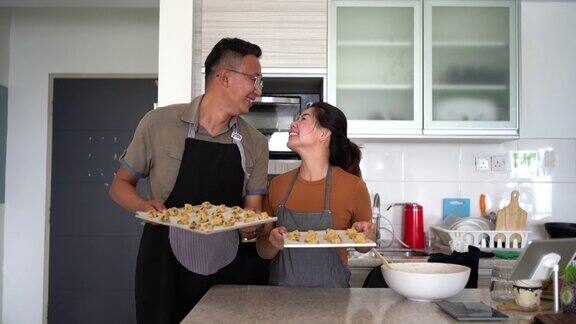 微笑的亚洲中国夫妇拿着饼干面团烘烤