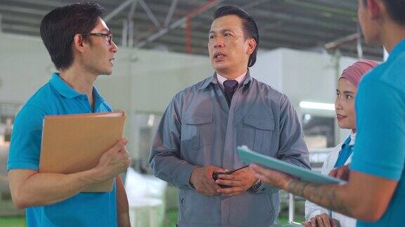 亚洲工厂经理与他的团队在装瓶厂生产线上讨论生产计划