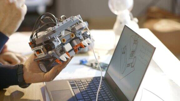 在计算机科学课堂上老师检查他的学生为学校项目绘制的程序机器人