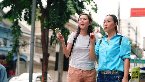 两个女游客在热闹的街头市场享用冰淇淋
