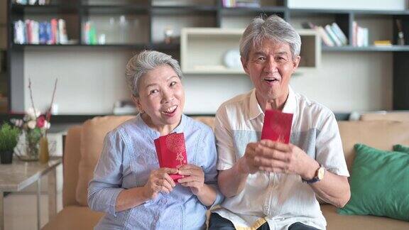 过年的老两口爷爷奶奶在客厅拿着红包看镜头