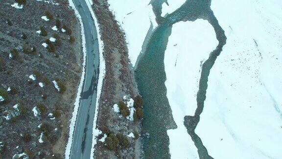 印度喜马偕尔邦拉胡尔和斯皮提山区结冰河流附近空旷的道路上行走的4K鸟瞰图冬季道路的俯视图