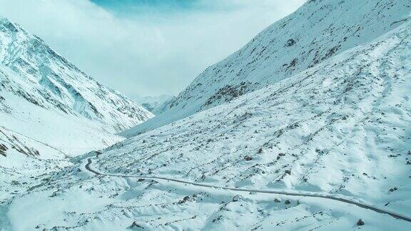 在印度喜马偕尔邦拉胡尔4K航拍的冬季大雪覆盖的空旷山路风景优美的公路旅行可以看到雪山旅游和假期