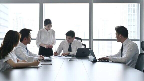 年轻的中国高管在会议室向CEO展示文件