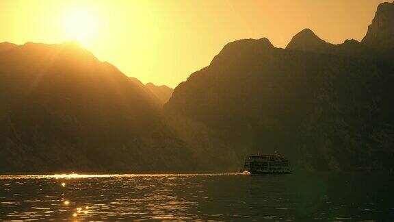 SLOMO客船在日落时沿着橙色天空下的山脉在加尔达湖上行驶