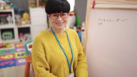 年轻的中国女幼儿园老师微笑自信地坐在幼儿园的椅子上