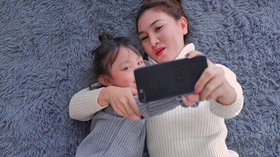 POV:6岁的亚洲母亲和女儿在家庭客厅里通过智能手机和视频会议技术进行视频通话社会电话会议