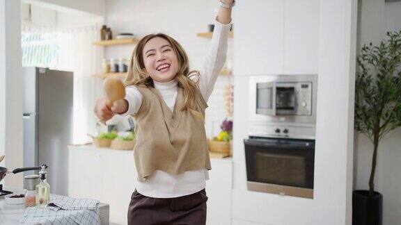 4K亚洲女人在厨房做饭时唱歌跳舞