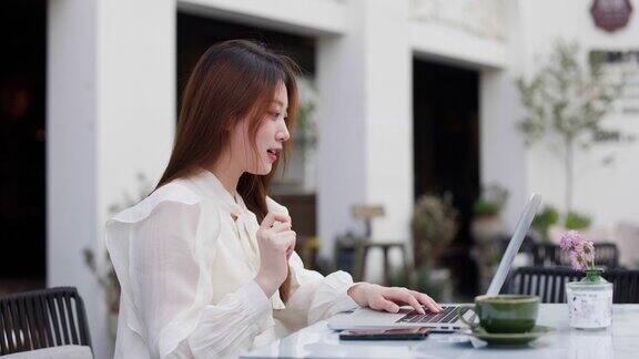 一位女商人在户外咖啡店用笔记本电脑进行视频会议