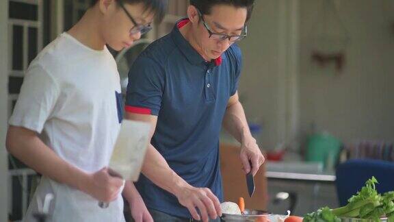 亚洲华人父亲儿子在厨房做饭周末在家后院为家人准备晚餐