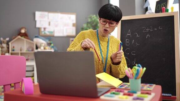 年轻的中国女幼师在幼儿园上在线课展示铅笔的颜色