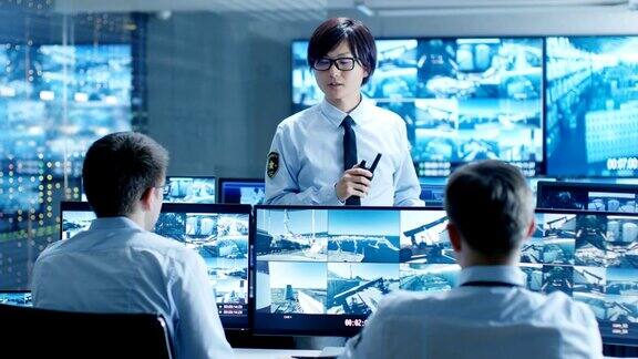 在安全控制室首席监控官为他的两个下属举行简报会多个屏幕显示他们保护重要的对象