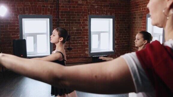 芭蕾舞训练-两个芭蕾舞女演员穿着黑色的套装在镜子前训练和她们的教练