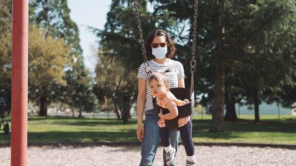族裔母亲和蹒跚学步的女儿在公园荡秋千