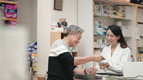 亚洲华人老人在药房柜台用信用卡支付非接触式支付