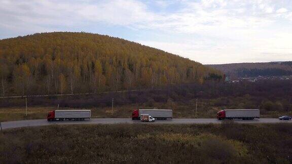 货车和汽车行驶在郊区的道路上背景是秋天的森林