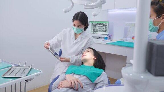 年轻女牙医拿着数码片给年轻女孩病人建议或咨询