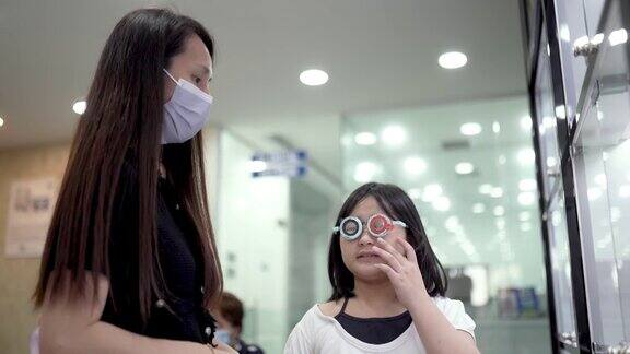 亚洲华裔女性眼科医生在检查光学实验室使用试验框架与儿童患者