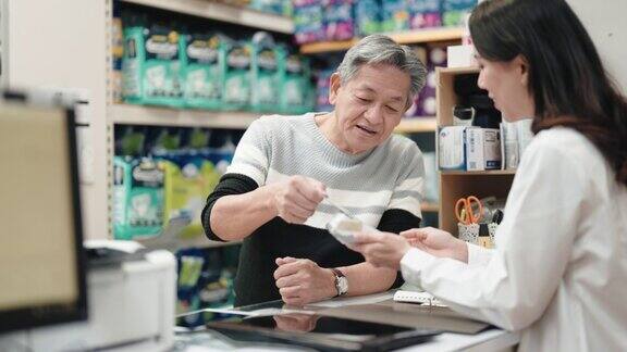 亚洲华人老人在药房柜台用信用卡支付非接触式支付