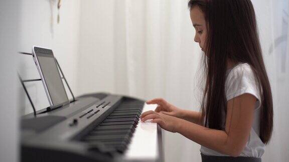 一个小女孩通过视频学习弹钢琴2019冠状病毒病期间的在线远程学习