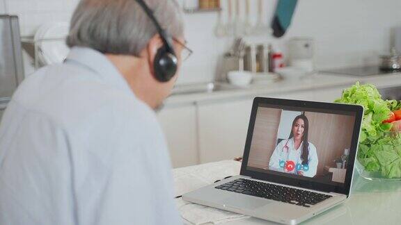 亚洲资深男士在家客厅与医生视频通话病人老人咨询全科医生应用电脑医生和顾问在线和远程医疗