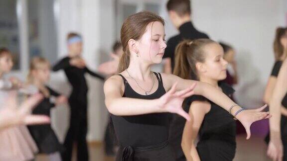 集中的白人女孩在舞蹈学校与同学排练拉丁舞动作聚焦美丽的孩子和青少年在舞蹈工作室的慢动作