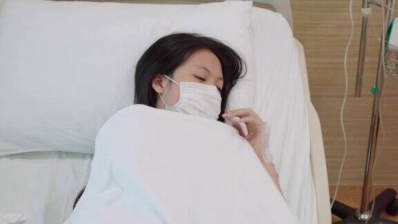 两张蒙面亚洲少女在医院病床上咳嗽的照片
