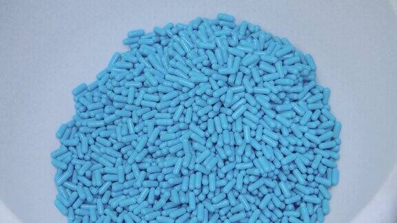 产生了蓝色的胶囊落在容器里药品生产工厂生产的药片的特写制药工业