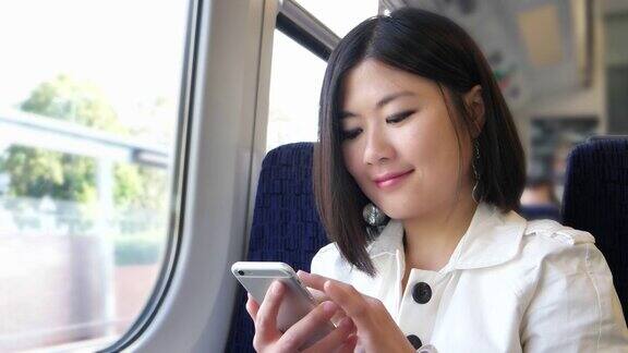 年轻的亚洲女子在火车上发短信