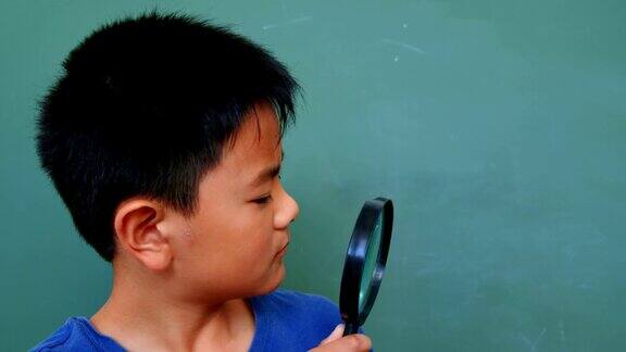 正面的亚洲学生看通过放大镜在教室在学校4k