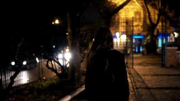 后视镜的女游客背包走在黑暗的公园附近的路深夜独自