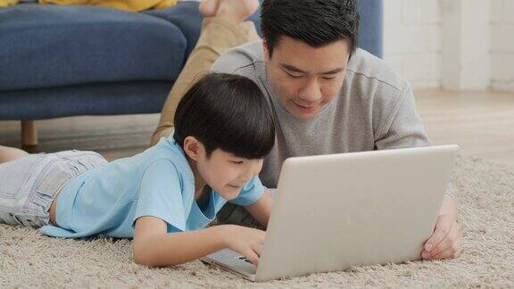 父子在家里一起使用电脑心情愉快家庭、科技和生活理念