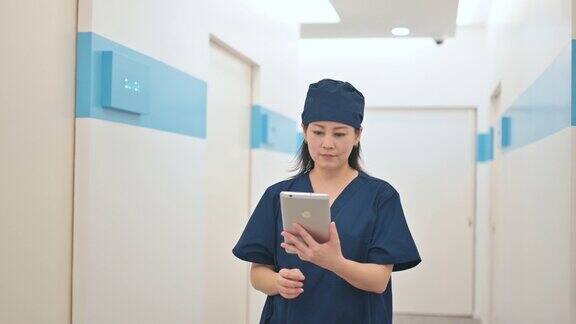 亚裔华裔女外科医生用平板电脑走在医院走廊上