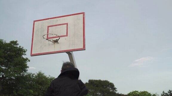一个亚洲的中国老男人在篮球场练习篮球比赛在早上跳投