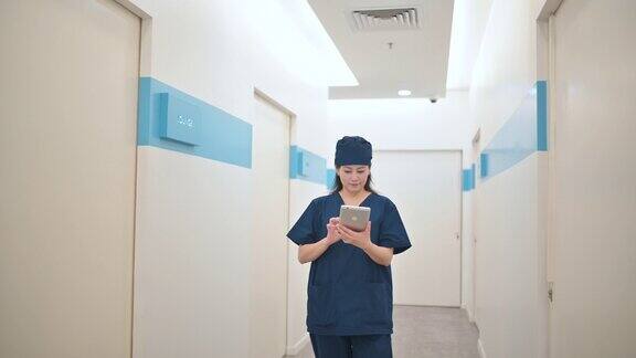 亚裔华裔女外科医生用平板电脑走在医院走廊上