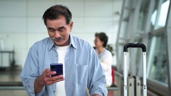 一名亚洲老人在机场使用智能手机