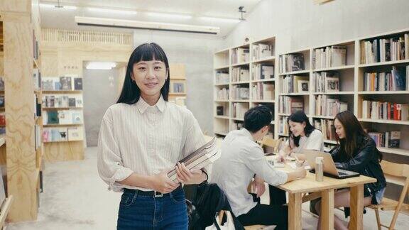 一位年轻美丽的亚洲女学生站在图书馆的肖像