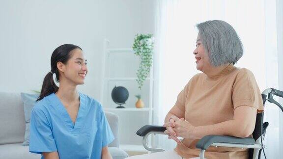 亚洲年轻的护理人员在家里照顾轮椅上的老年妇女有吸引力的美丽的护士医生感觉快乐同时谈论和支持老年老年成熟的女性病人在养老院照顾
