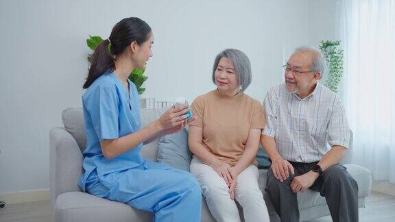亚洲老年夫妇咨询护理妇女在养老院医师治疗师药剂师女孩拿着药瓶在家里的客厅向爷爷奶奶解释处方