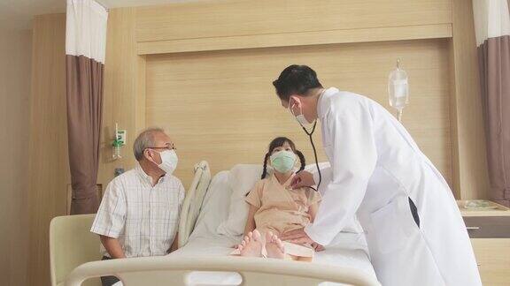 男医生检查病床上小女孩的心率、脉搏和提供健康保健咨询