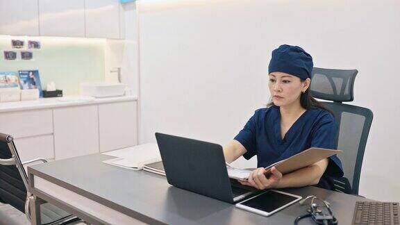 在医生办公室工作的亚裔华裔女医生阅读报告