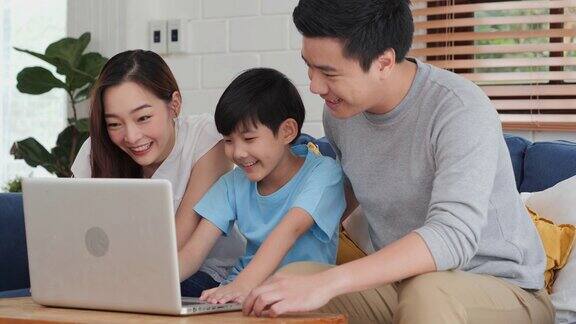 快乐的家庭在家里一起使用笔记本电脑他们用电脑一起看电影或研究信息家庭、科技和生活理念
