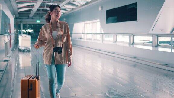 幸福微笑的亚洲女乘客带着黄色行李箱走在机场候机楼女乘客在前往航班登机口的路上旅游旅行