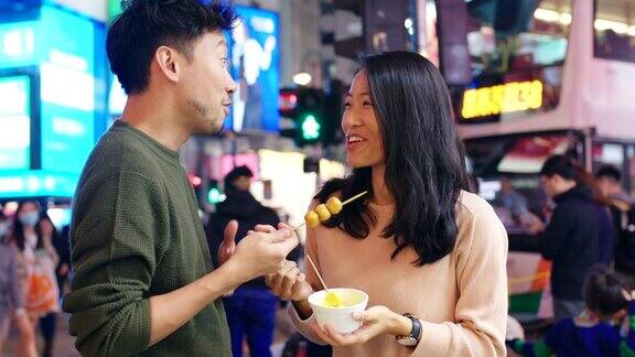 SLOMO手持中景拍摄一对年轻夫妇在香港街头吃小吃