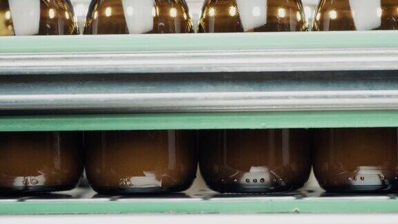 在工厂的生产线上一排玻璃瓶被液体填充满制药业医疗用品药品生产自动装瓶线关闭了慢动作4K视频