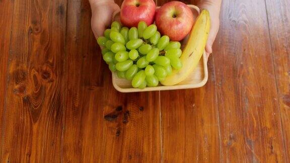 手拿着一个水果放在木桌上
