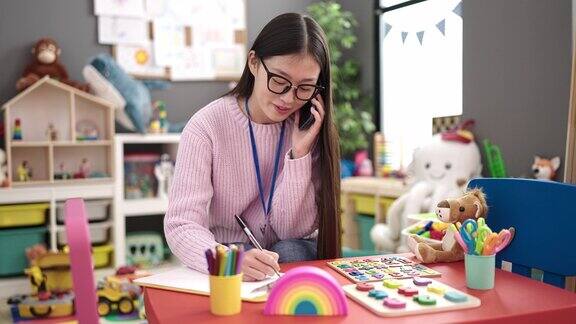 年轻的中国女幼儿教师在幼儿园用智能手机写文件