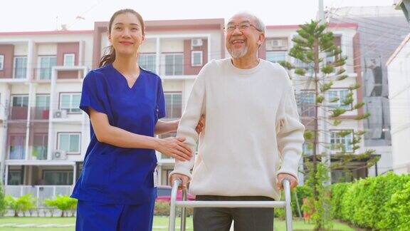 亚洲年轻的护理护士支持年长的男性在户外行走专科女医生帮助和照顾老年成年男病人在疗养院的公园做物理治疗